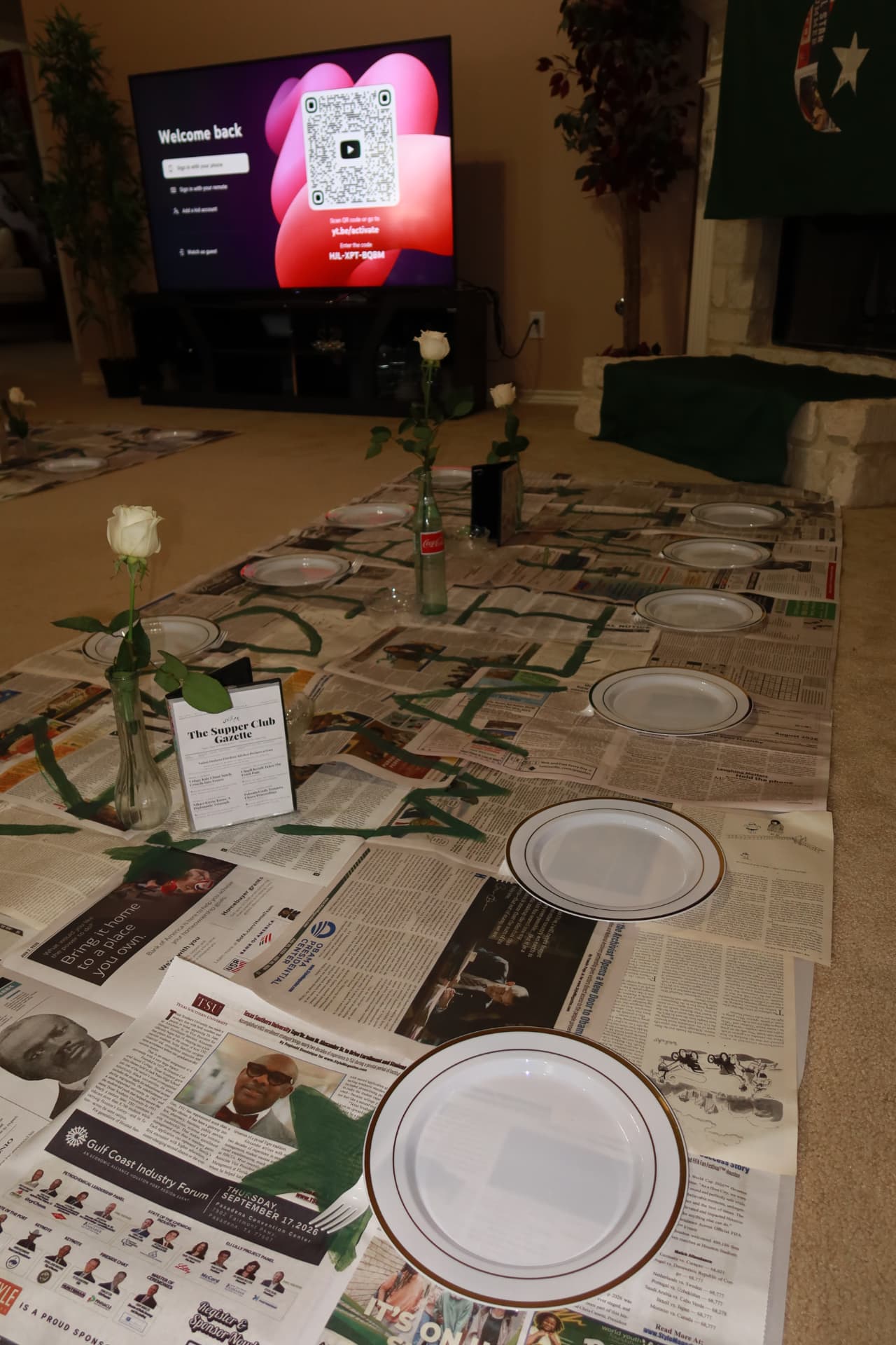 Newspaper-covered long table set with white roses