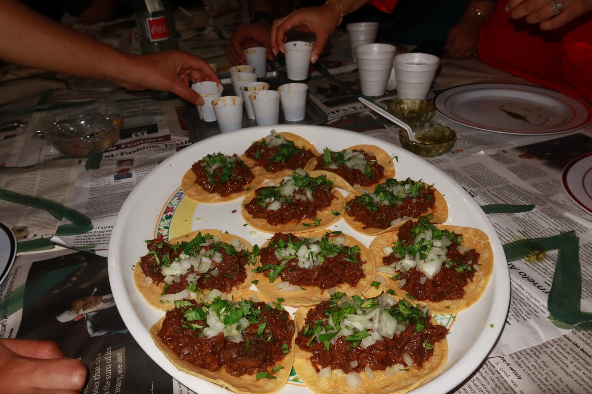 A platter of birria tacos on the newspaper-covered table